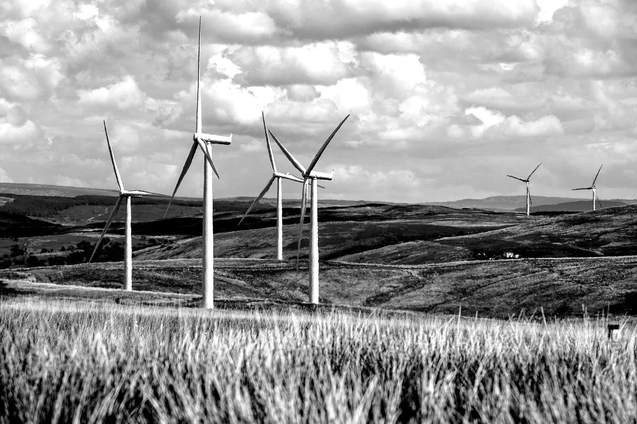 Éoliennes alignées sur des collines cultivées, sous un ciel nuageux